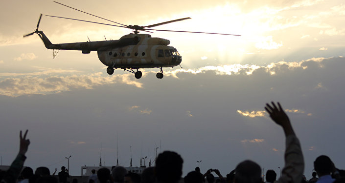 Líbios acenar e piscar o sinal para a vitória em um helicóptero militar como moscas durante uma exibição militar na cidade costeira da Líbia de Benghazi em 15 de Maio de 2012.