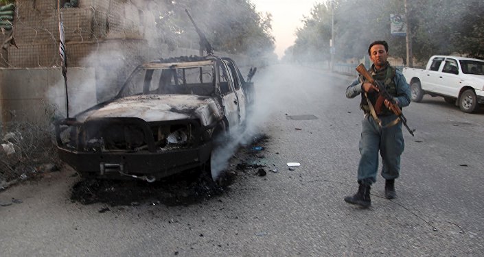 Um afegão patrulha policial ao lado de um veículo em chamas na cidade de Kunduz, Afeganistão 01 de outubro de 2015