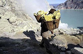 Sulfur miner at Ijen volcano carrying baskets of solid sulfur up from the crater.